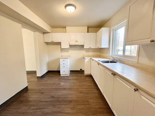 an empty kitchen with white cabinets and a window