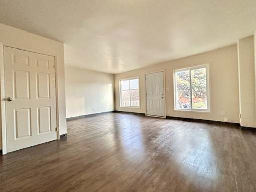 an empty living room with wood floors and a white door