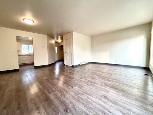 an empty living room with a hard wood floor