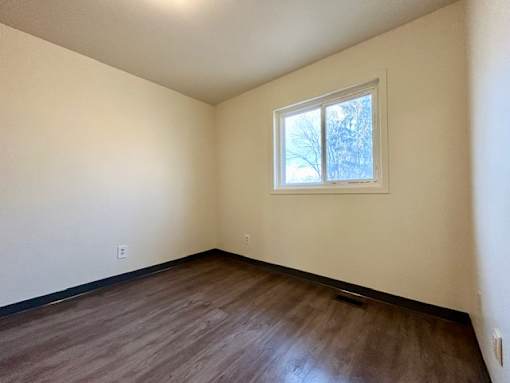 an empty room with a window and wooden floors