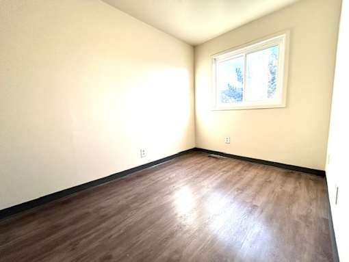 an empty room with wood floors and a window
