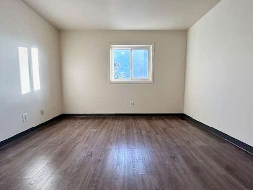 an empty room with wooden floors and a window