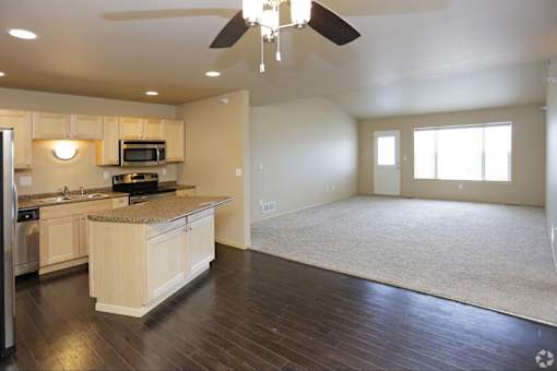 A spacious kitchen with wooden floors and a ceiling fan.