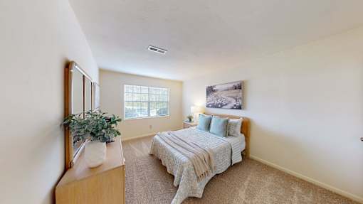 A bedroom with a bed, dresser, and mirror.