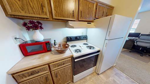 A kitchen with wooden cabinets and a red microwave.