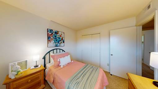 A bedroom with a bed, nightstand, and a painting on the wall.