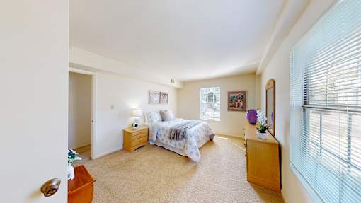 A bedroom with a bed, nightstand, and window.