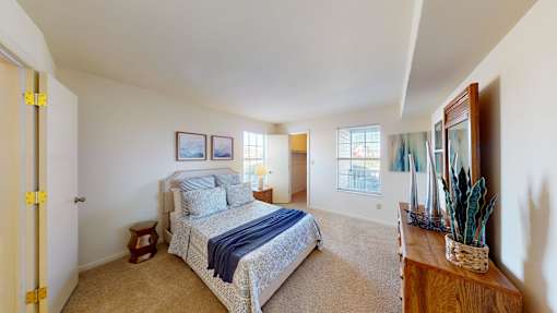 A bedroom with a bed, a side table, and a window.