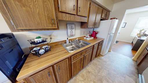 A kitchen with wooden cabinets and a black fridge.