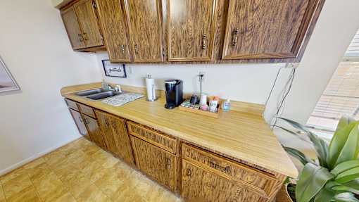 A kitchen with wooden cabinets and a countertop with a coffee maker and other items.