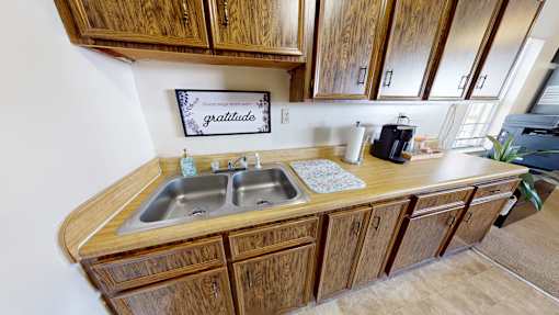 A kitchen with wooden cabinets and a sign that says "Good Gratitude".