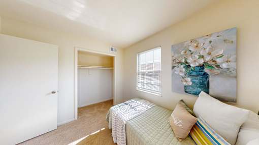 A bedroom with a bed, pillows, and a painting on the wall.
