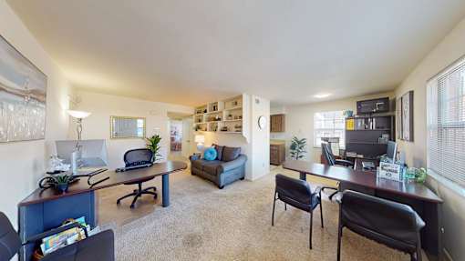 a living area with wall-to-wall carpeting and built-in bookshelves