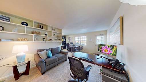 A well-lit room with a desk, chair, and a couch.