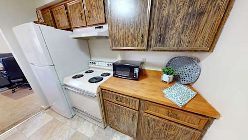 A kitchen with a white refrigerator, a white stove, and wooden cabinets.