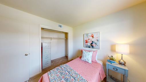 A bedroom with a pink bedspread and a bed with a floral pattern.