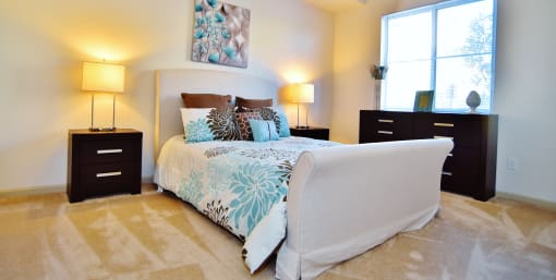 a bedroom with a bed and two nightstands and a window