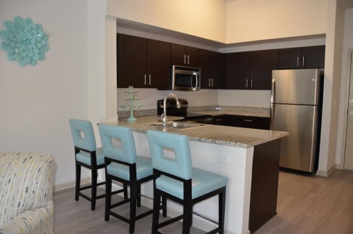 a kitchen with an island with four blue chairs in front of it