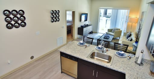 a kitchen with a granite counter top and a living room with a couch and tv