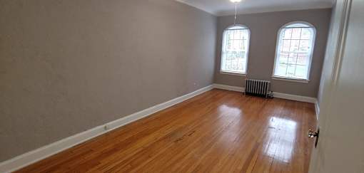 an empty living room with wood floors and two windows