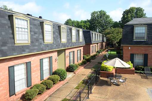 A sunny day at a brick apartment complex with a patio and a table.