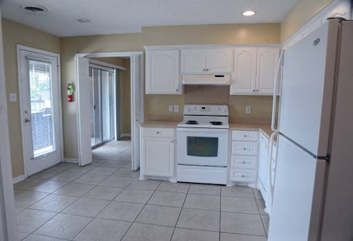 A kitchen with white appliances and cabinets.