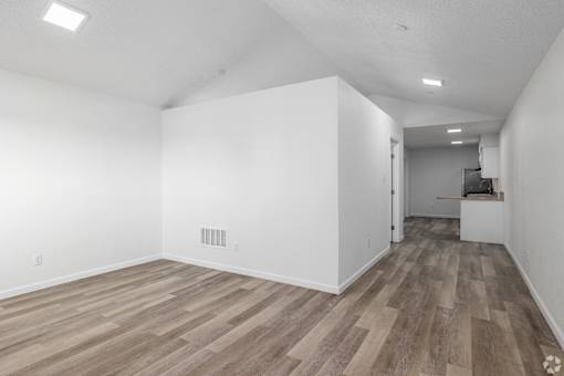 A room with wooden flooring and white walls.
