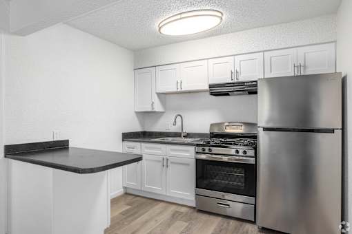 A kitchen with white cabinets and a stainless steel refrigerator.