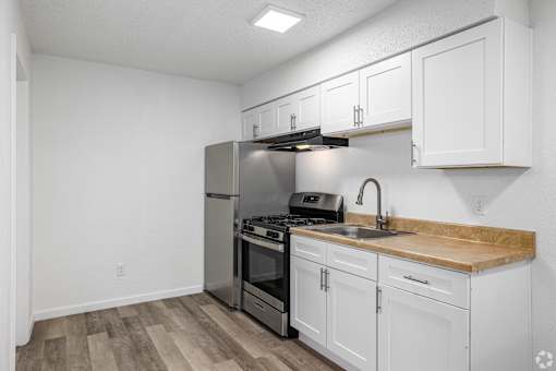 A kitchen with white cabinets and a wooden countertop.