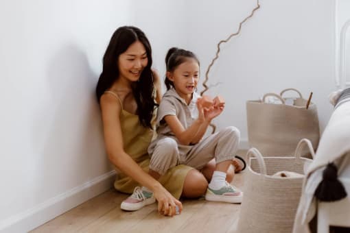 A woman and a child are sitting on the floor playing with a toy.