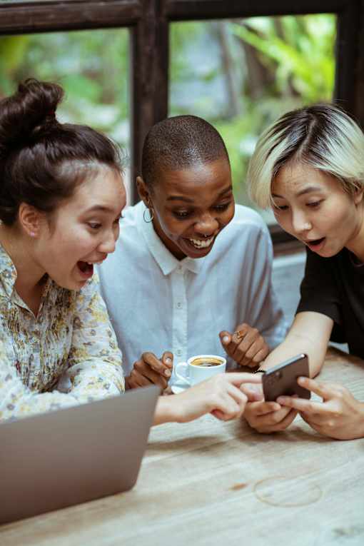 Three people are looking at a smartphone together.