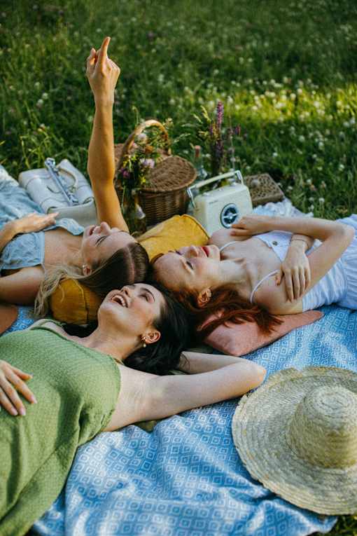 Three people are lying on a blanket in a field.