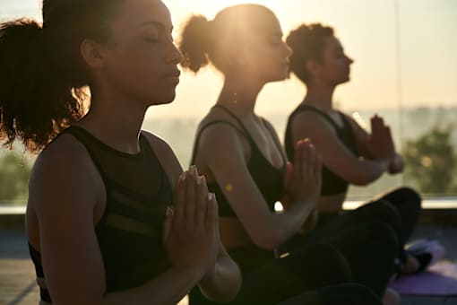 Three people are sitting cross-legged and meditating.