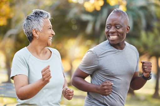 An older couple jogging together in a park.