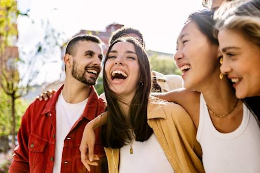 Three people are laughing together outdoors.
