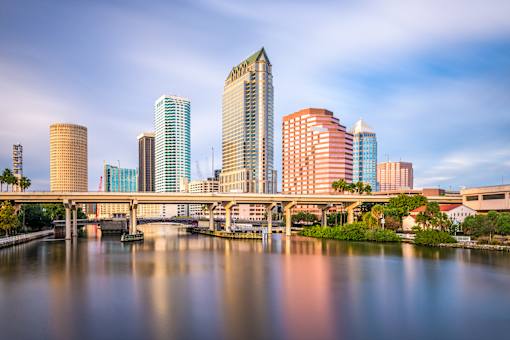 A cityscape with a river in the foreground and a bridge crossing it.