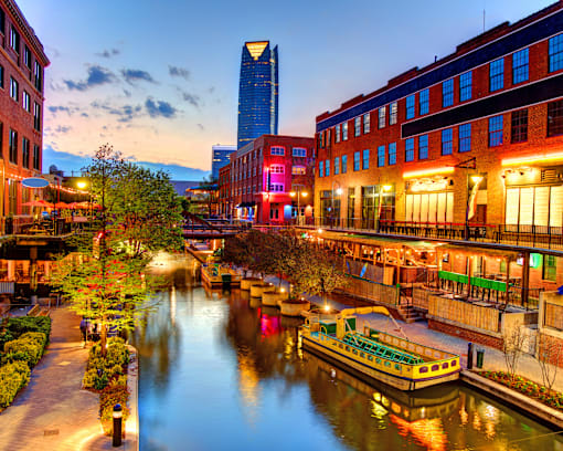 A boat is docked at a canal in a city.
