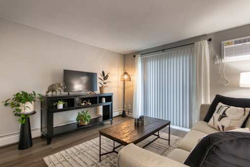 A living room with a television, a couch, a coffee table, and a plant in a 1 bedroom, 1 bath 560 square foot apartment at Aspen Village Apartments in the Westwood neighborhood of Cincinnati, OH.