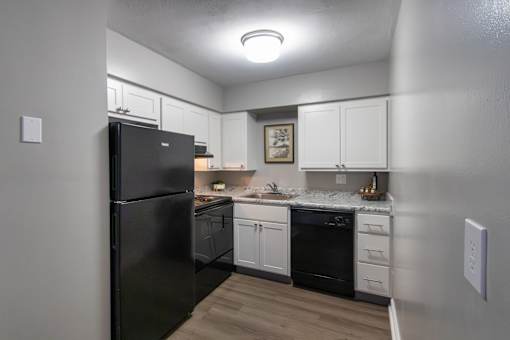 A black refrigerator is in a kitchen with white cabinets in a 1 bedroom, 1 bath 560 square foot apartment at Aspen Village Apartments in the Westwood neighborhood of Cincinnati, OH.