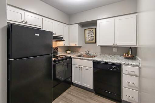 A black refrigerator is in a kitchen with white cabinets in a 1 bedroom, 1 bath 560 square foot apartment at Aspen Village Apartments in the Westwood neighborhood of Cincinnati, OH.