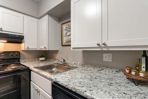 A kitchen with a granite countertop and white cabinets in a 1 bedroom, 1 bath 560 square foot apartment at Aspen Village Apartments in the Westwood neighborhood of Cincinnati, OH.