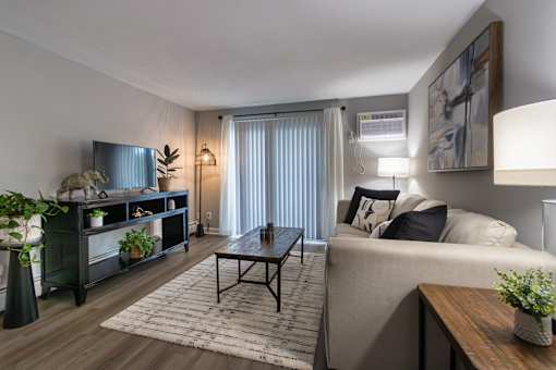 A living room with a couch, coffee table, and plantsin a 1 bedroom, 1 bath 560 square foot apartment at Aspen Village Apartments in the Westwood neighborhood of Cincinnati, OH.