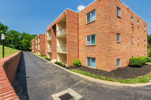 Side view of a brick apartment building with balconies and paved drive at Aspen Village
