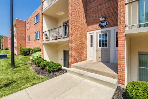 Apartment entry with covered doorway, balconies, and manicured shrubs at Aspen Village