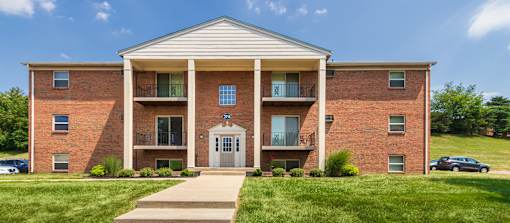 Brick apartment building with secure entry, balconies, and sidewalk at Aspen Village