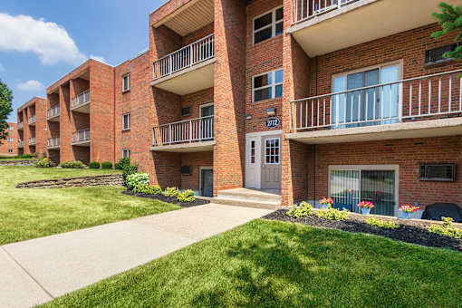 Brick apartment building with balconies, secure entry , and landscaped walkway at Aspen Village