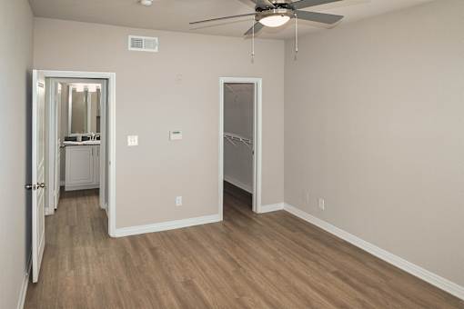 Bedroom with wood-look flooring, ceiling fan in a one-bedroom apartment with 1-car garage