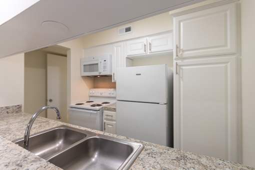 Kitchen with white cabinets and white appliances in a 2 bedroom, 1.5 bath 846 sq ft apartment home at The Biltmore Apartments located in the Vickery Midtown neighborhood of Dallas, TX.