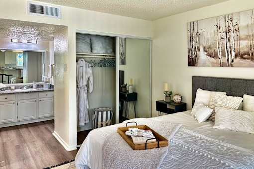 Sleeping and living area in an Efficiency apartment at Cambridge Court Apartments in Dallas, Texas, showing the bed area, and access toward the bathroom and closet.