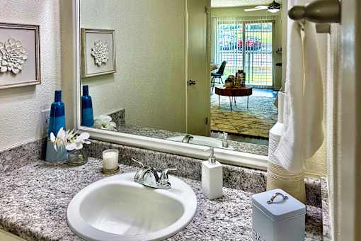 Bathroom in an Efficiency apartment at Cambridge Court Apartments in Dallas, Texas, featuring a vanity, mirror, toilet, and tub/shower combination.